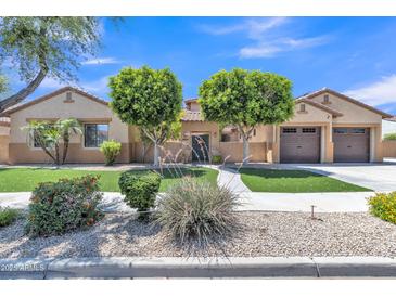 Charming home featuring manicured landscaping, vibrant green lawn, and a welcoming facade at 2652 N 143Rd Dr, Goodyear, AZ 85395