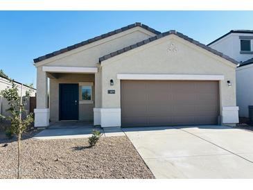 Inviting single-story home featuring a low-maintenance desert landscape, two car garage, and a covered entryway with a dark blue front door at 5019 E Umber Rd, San Tan Valley, AZ 85143
