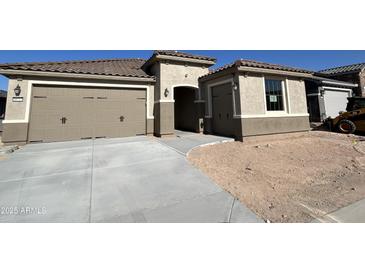 Beautiful home exterior featuring a three-car garage, neutral tones and a well-manicured lawn at 18717 N 267Th Dr, Buckeye, AZ 85396