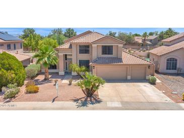 Two-story home with neutral stucco, clay tile roof, three-car garage, desert landscaping, and mature palm trees at 981 N Quail Ln, Gilbert, AZ 85233
