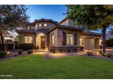 Elegant home featuring beautiful stone accents, arched entryway, landscaped yard, and an American flag at 5434 E Barwick Dr, Cave Creek, AZ 85331
