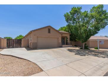 Tan single-story home featuring a two-car garage and desert landscaping in a suburban neighborhood at 10735 E Kilarea Ave, Mesa, AZ 85209