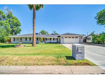 Charming single-Gathering home featuring lush front lawn, mature palm tree and two-car garage at 1208 E Tuckey Ln, Phoenix, AZ 85014