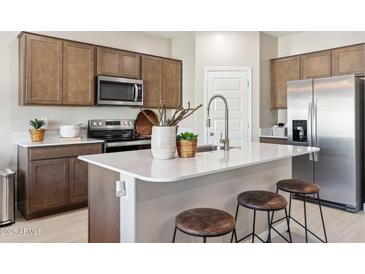 Modern kitchen with stainless steel appliances, wood cabinets, a white countertop island with stools at 1648 S 241St Ave, Buckeye, AZ 85326