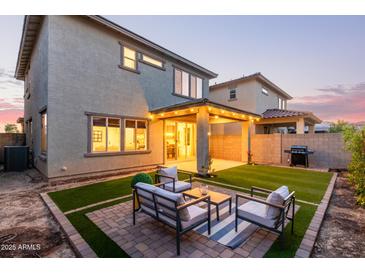 An inviting backyard with a seating area, lush lawn, and a covered patio with string lights for outdoor entertaining at 2067 N Marketside Ave, Buckeye, AZ 85396