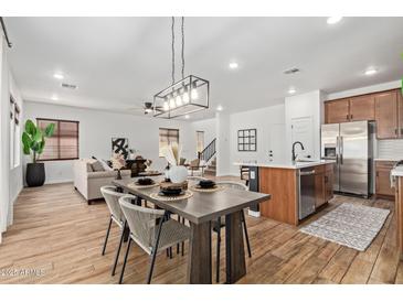 Dining area with modern chandelier, wood table set, and seamless flow to the kitchen and living room at 2067 N Marketside Ave, Buckeye, AZ 85396