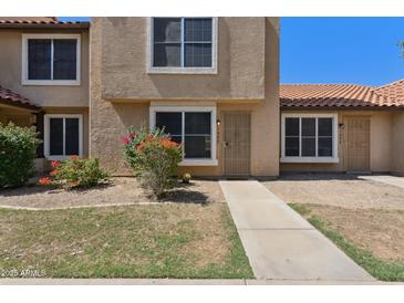 Tan stucco townhome with a red tiled roof and a small yard with desert landscaping at 4601 N 102Nd Ave # 1055, Phoenix, AZ 85037