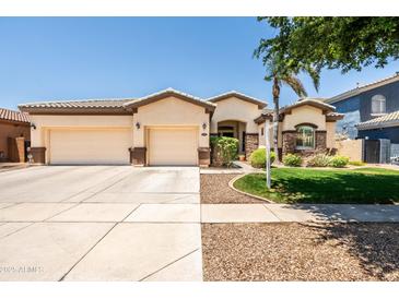 Charming single-story home featuring a spacious three car garage, manicured lawn, and stone accents at 4614 E Reins Rd, Gilbert, AZ 85297