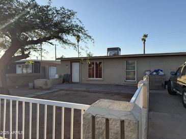 Cozy home exterior features a quaint yard and neutral-toned facade, with mature trees providing shade at 3946 W Holly St, Phoenix, AZ 85009