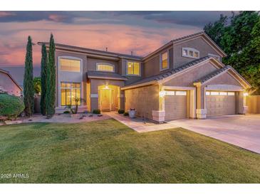 Inviting two-story home featuring a manicured lawn, desert landscaping, and a convenient three-car garage at 6961 W Honeysuckle Dr, Peoria, AZ 85383