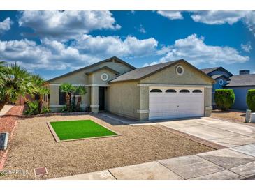 Inviting single-story home with a well-manicured desert landscape, lush green turf and a two-car garage at 8501 W Highland Ave, Phoenix, AZ 85037