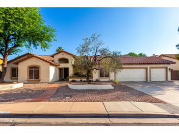 Charming single-story home featuring a three-car garage, well-maintained yard with mature trees, and a red tile roof at 882 N Concord Ave, Chandler, AZ 85225