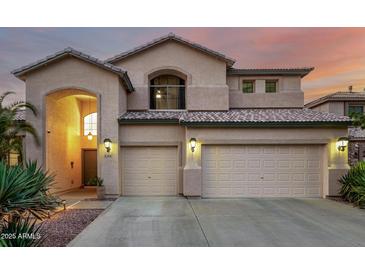 Charming two-story home with a three-car garage and desert landscaping is bathed in a warm sunset glow at 13636 W Calavar Rd, Surprise, AZ 85379