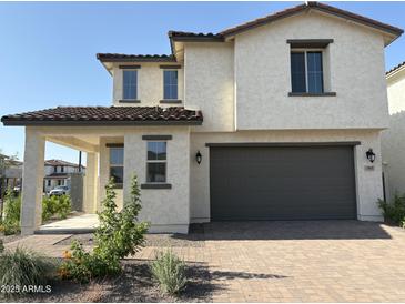 Two story home featuring neutral stucco, a two-car garage, covered entry, and red-tile roof in a suburban neighborhood at 3363 S 180Th Ln, Goodyear, AZ 85338
