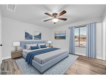Comfortable bedroom features hardwood floors, ceiling fan, stylish decor, and lots of natural light at 3444 E Paradise Dr, Phoenix, AZ 85028
