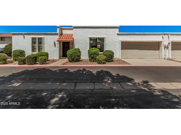 Charming townhome featuring white stucco, a red tile awning, a garage, and well-maintained landscaping at 5314 N Las Casitas Pl, Phoenix, AZ 85016