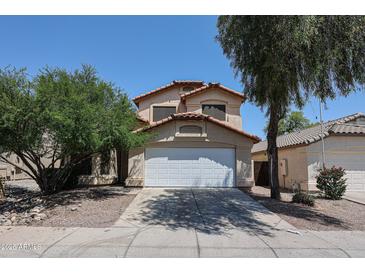 Two story home featuring a driveway, two car garage, desert landscaping, and a red tile roof at 12408 W Orange Dr, Litchfield Park, AZ 85340