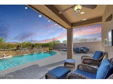 Inviting covered patio with ceiling fan and wicker furniture overlooks pool with stone waterfall feature at 778 W Lowell Dr, San Tan Valley, AZ 85140