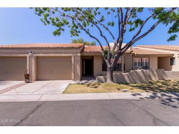 Charming single-story home featuring a two-car garage and mature shade tree in the front yard at 1021 S Greenfield Rd # 1211, Mesa, AZ 85206