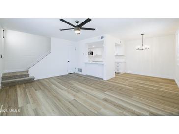 Open-concept living room with wood floors and a staircase, flowing into the bright kitchen area at 948 S Alma School Rd # 1, Mesa, AZ 85210