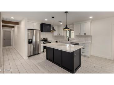 Modern kitchen boasts white cabinets, a black island with marble countertop, and stainless steel appliances at 313 N 101St Way, Mesa, AZ 85207