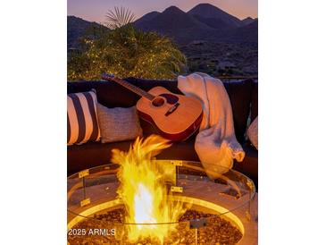 Inviting outdoor space featuring a cozy firepit, sofa, guitar, and scenic mountain views, perfect for relaxation and entertainment at 15054 E Sundown Dr, Fountain Hills, AZ 85268