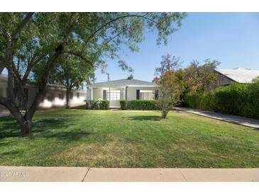 Charming single-story home with lush green lawn, mature trees, and covered front porch at 1609 W Lewis Ave, Phoenix, AZ 85007