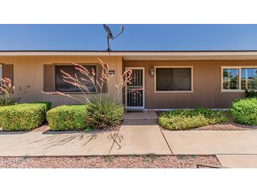 Inviting front entrance with security screen door and well-maintained landscaping at 10520 W Coggins Dr, Sun City, AZ 85351