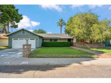 Charming single-Gathering home featuring a lush lawn, mature trees, and a brick-accented facade at 216 E Harmont Dr, Phoenix, AZ 85020