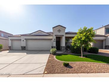 Attractive single-Gathering home featuring a three-car garage and manicured front yard with green grass and decorative rock at 3026 N 305Th Dr, Buckeye, AZ 85396