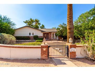 Charming home featuring a well-manicured front yard with a brick and stucco fence, gate, and mature landscaping at 5744 E Oak St, Scottsdale, AZ 85257