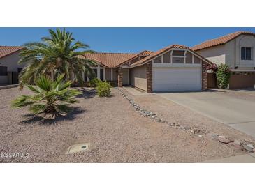 Charming single-story home with desert landscaping and a spacious two-car garage and a red tile roof at 5911 E Evergreen St, Mesa, AZ 85205