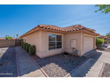 Side view of house featuring desert landscaping, and red tiled roof with tan paint at 7531 W Kimberly Way, Glendale, AZ 85308
