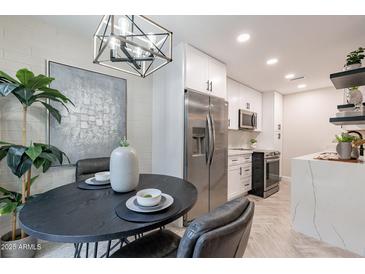 Eat-in kitchen featuring stainless steel appliances, quartz counters, and a modern light fixture at 1005 N Granite Reef Rd, Scottsdale, AZ 85257