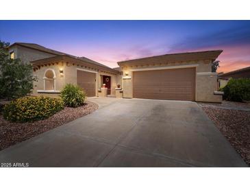 Charming home featuring a three-car garage, desert landscaping, and a welcoming red front door at 42726 N Livingstone Way, Anthem, AZ 85086
