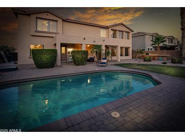 Tranquil backyard with a shimmering pool, covered patio, and ample green space for outdoor enjoyment at 7156 S Forest Ave, Gilbert, AZ 85298