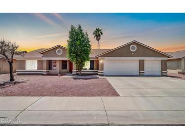 Charming single-story home with a three car garage and well-kept yard at sunset at 10943 W Alice Ave, Peoria, AZ 85345