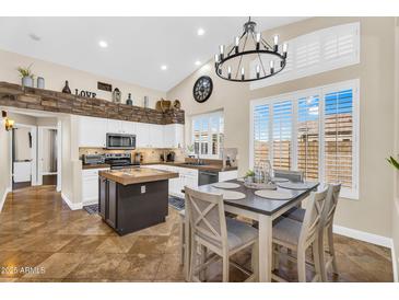 Bright kitchen features white cabinets, center island, stone accent wall and eat-in dining area at 6352 W Hackamore Dr, Phoenix, AZ 85083