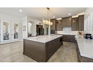 Open kitchen featuring a large island with white marble countertops, stylish cabinets, and modern stainless appliances at 5332 E Thunder Hawk Rd, Cave Creek, AZ 85331