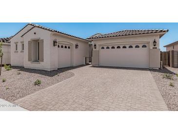 Two-car garage with desert landscaping and a brick driveway leading up to the house at 16981 W Cameron Dr, Surprise, AZ 85388