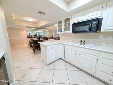 Bright kitchen featuring white cabinetry, modern appliances, and tile flooring at 17404 N 99Th Ave # 126, Sun City, AZ 85373