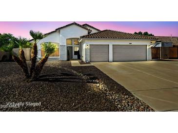 Charming single-story home boasts a tiled roof, two-car garage, and well-maintained desert landscaping at 6935 W Monte Lindo St, Glendale, AZ 85310