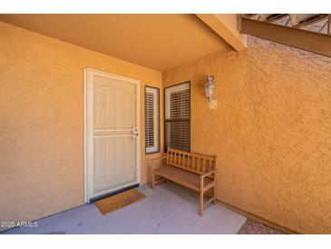 Inviting condo front entrance with a charming wooden bench, fresh paint, and ample natural light at 8787 E Mountain View Rd # 1110, Scottsdale, AZ 85258
