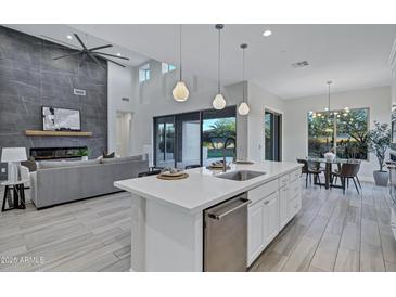 Modern kitchen features a large island, stainless steel appliances, and seamless connection to the living room and dining area at 11717 W Red Hawk Dr, Peoria, AZ 85383