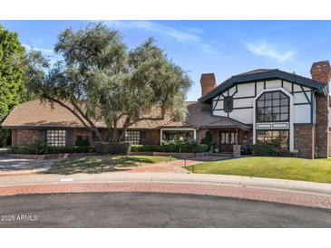 Charming two-story brick home featuring a manicured front lawn, mature tree, and brick driveway at 211 W Kaler Dr, Phoenix, AZ 85021