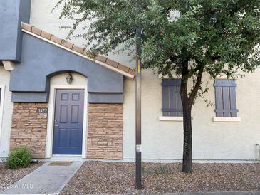 Charming townhouse features a blue front door, stone accents, and mature trees for added curb appeal at 2402 E 5Th St # 1472, Tempe, AZ 85288