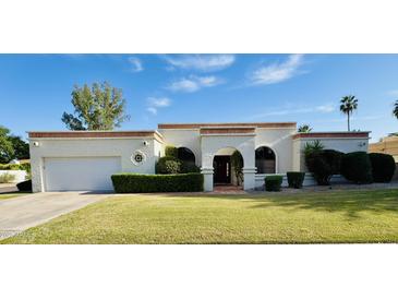 Charming, light-colored single-story home featuring a well-manicured lawn and covered entryway at 8413 E Belgian Trl, Scottsdale, AZ 85258