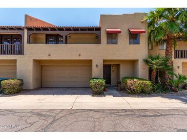 Inviting two-story condo showcasing a private garage, balcony, and lush tropical landscaping at 10235 N 31St St # 2, Phoenix, AZ 85028