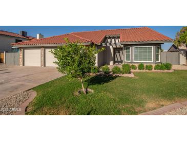 Charming home featuring a manicured lawn, mature tree, and a two-car garage at 11615 N 77Th Dr, Peoria, AZ 85345