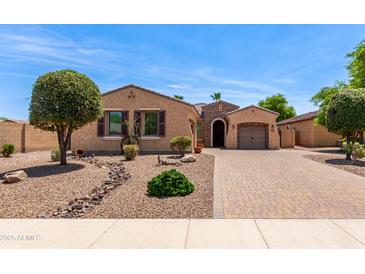 Charming single-story home with desert landscaping, brick driveway, and barrel roof accents at 1643 N 144Th Dr, Goodyear, AZ 85395